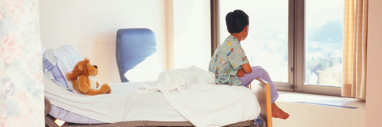 Young boy (6-7) sitting on hospital bed
