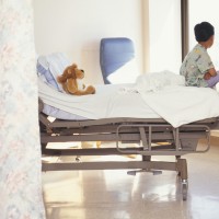 Young boy (6-7) sitting on hospital bed