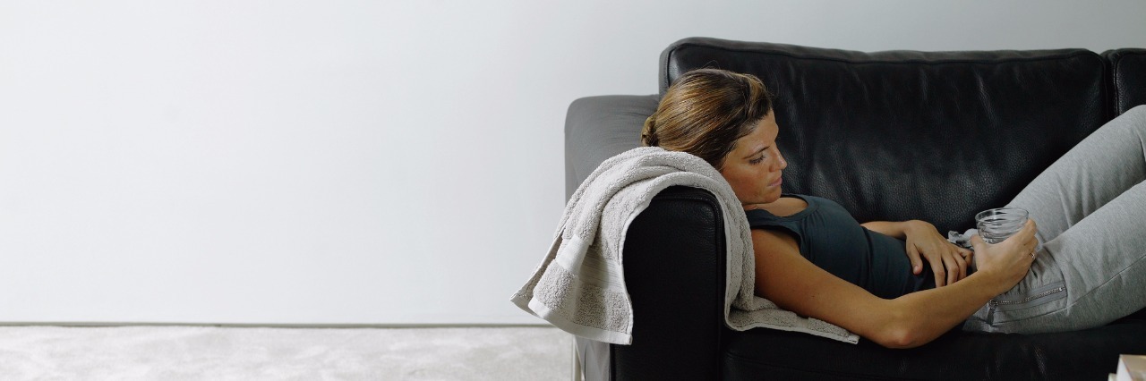 Chronic Pain and Learning to Pace Yourself Woman wearing sports clothes resting on sofa, holding drink