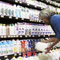 Mature woman reading milk label in supermarket, side view, close-up