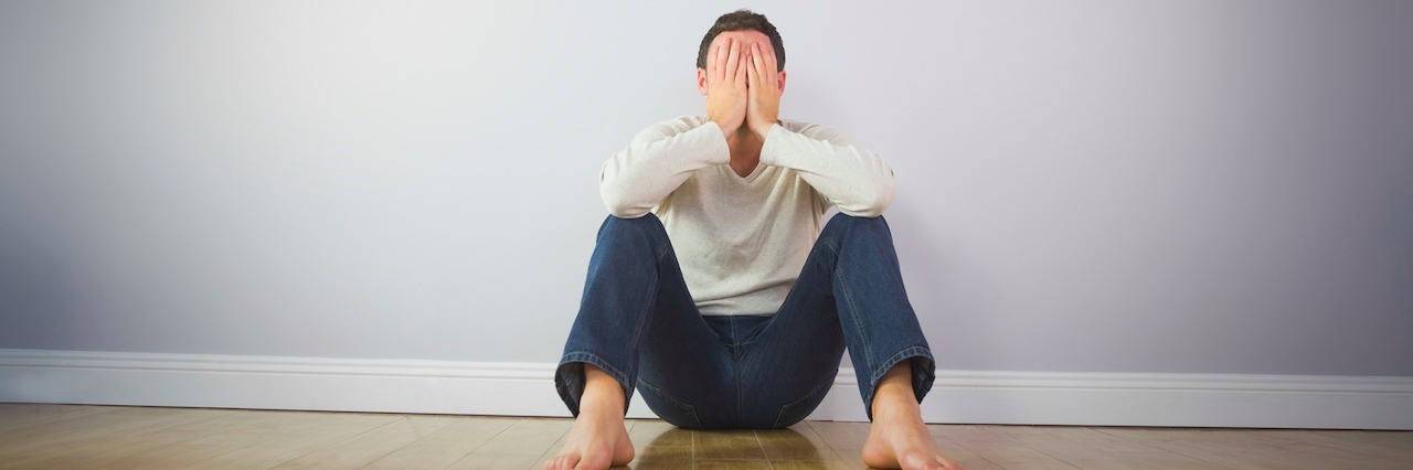 A man sitting down and covering his face