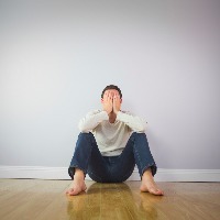 A man sitting down and covering his face