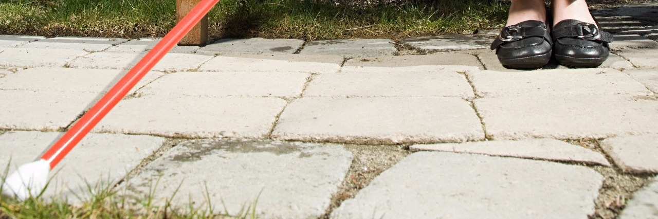 Struggling to Accept Using a Cane as a Legally Blind Person Blind woman with cane sitting on park bench.