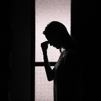 silhouette of woman holding head in dark room