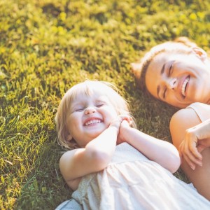 smiling mother and baby laying on meadow