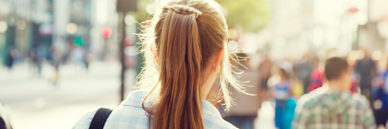 back of woman's head walking through city