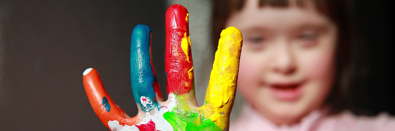 Donald Trump's Abortion Views Won't Help People With Disabilities Girl with Down syndrome. Her hand is covered in rainbow paint.