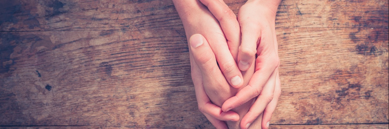 4 Phrases That Help Me Through Depression Close up on a man and a woman holding hands at a wooden table