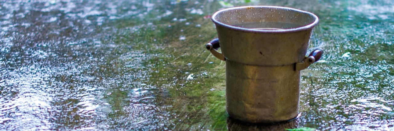 When Dissociative Identity Disorder Surfaces in an Adult Old metal bucket on a cement surface under the rain.