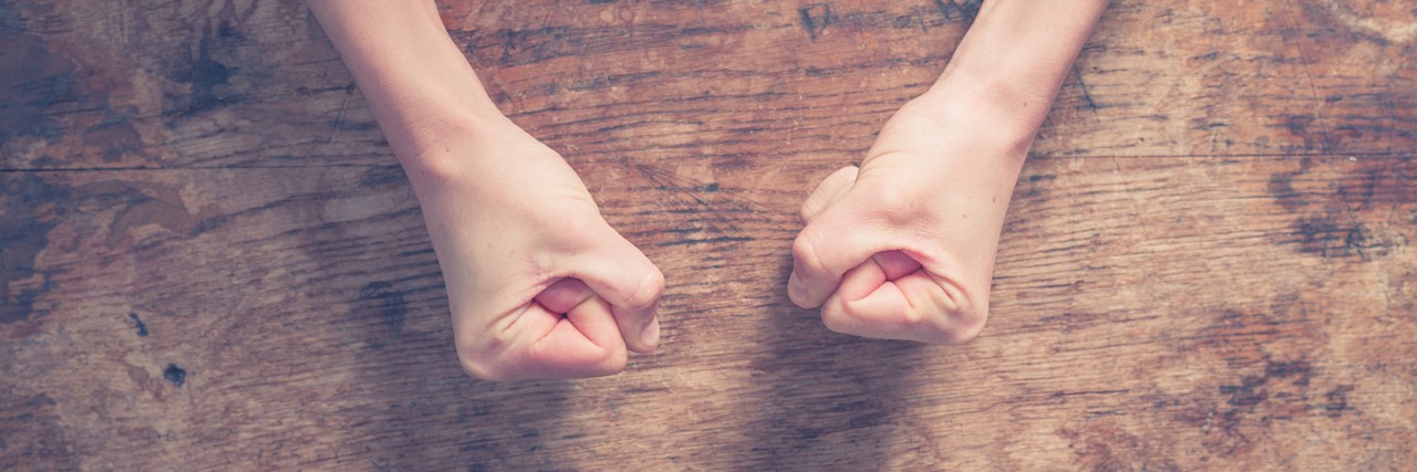 Letter About the Impact of an Eating Disorder Female fists clenched on a wooden table in anger