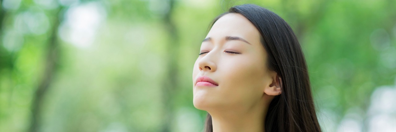 5 Quick Ways to Manage Anxiety young woman taking a deep breath outdoors