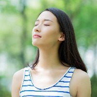young woman taking a deep breath outdoors
