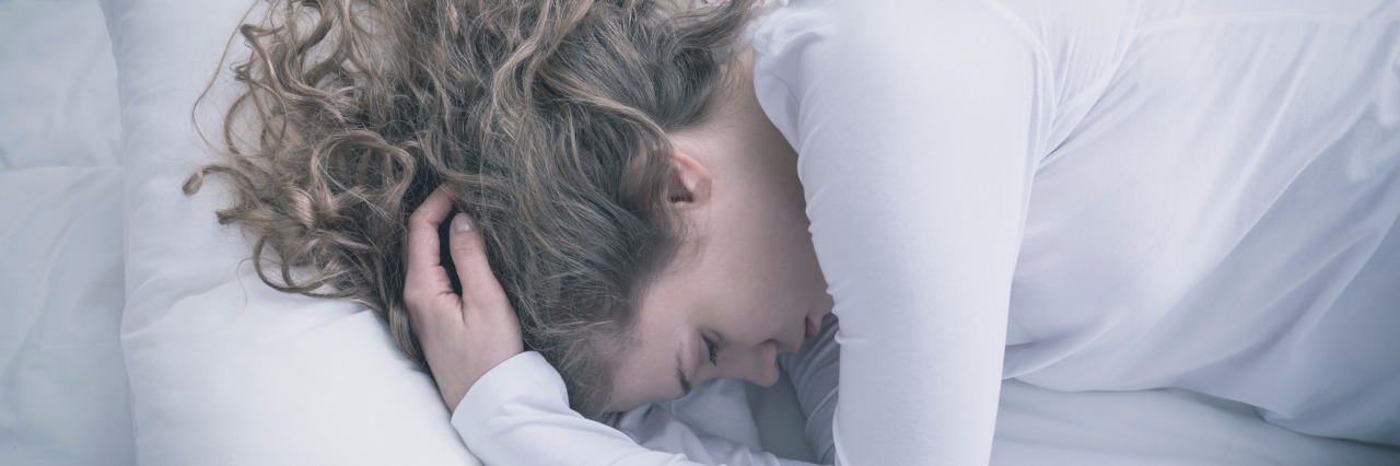 woman lying in bed holding head