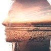 double exposure of a woman smiling and a photograph of a sunset on a beach