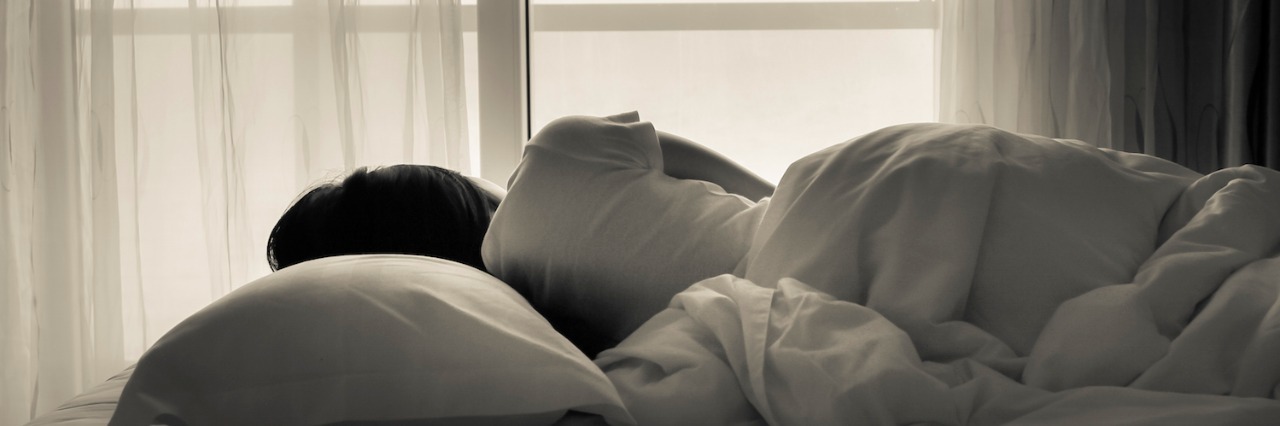 Autism: Having a Nightmare About My Parents Not Being Supportive Black and white photo of woman lying in bed, facing window