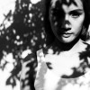 Young woman standing under tree shadows