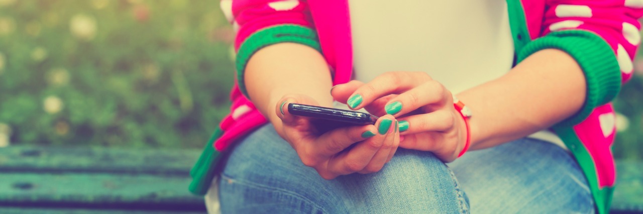 girl sitting on bench texting on phone