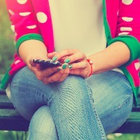 girl sitting on bench texting on phone