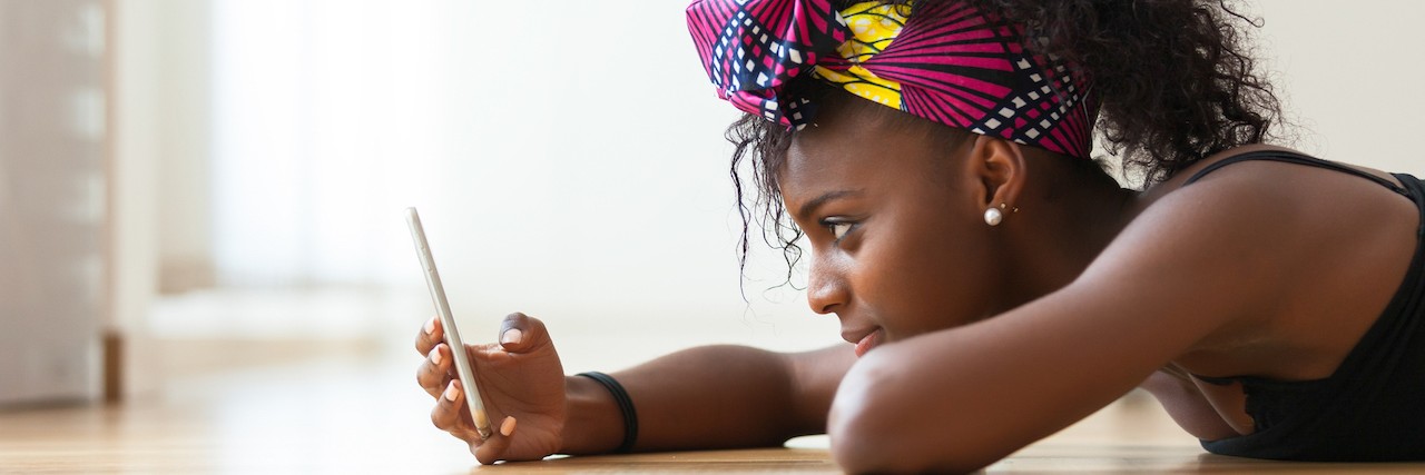 How to Respond When a Friend With Mental Illness Cancels Plans A woman laying on the floor looking at her phone