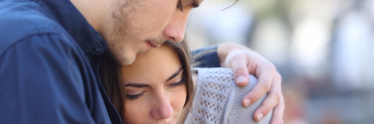 young man hugging and comforting female friend