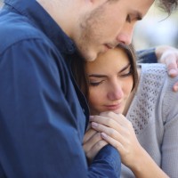young man hugging and comforting female friend