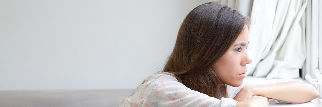 Young woman sitting alone looking out window