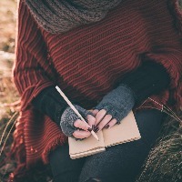 woman sitting outside and writing in her journal