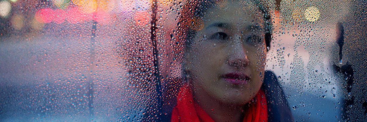 How I'm Dealing With Anger After My Husband's Suicide A woman behind a window covered in rain droplets