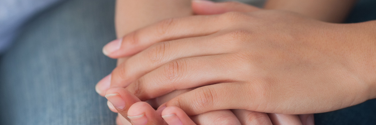 Tips for Supporting a Loved One With Scoliosis Close friends holding hands.