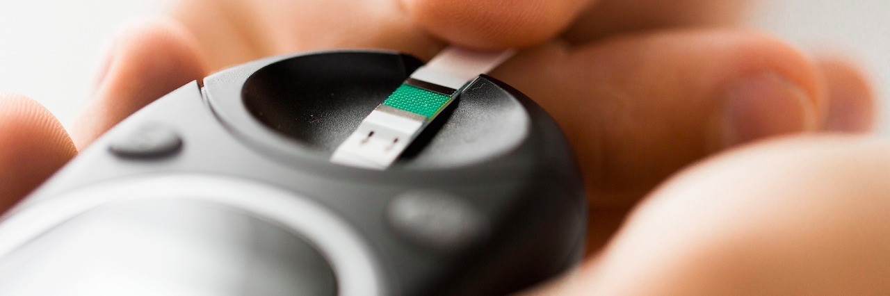 Diabulimia: Having Diabetes and an Eating Disorder close up of man checking blood sugar by glucometer