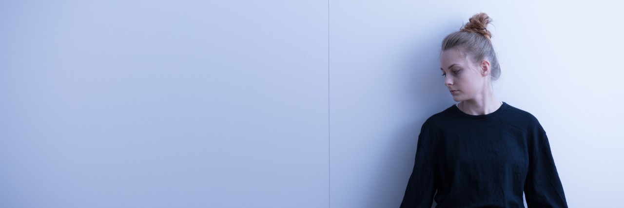 Explaining Anxiety and Worrying About 'What Ifs' teenage girl sitting against wall