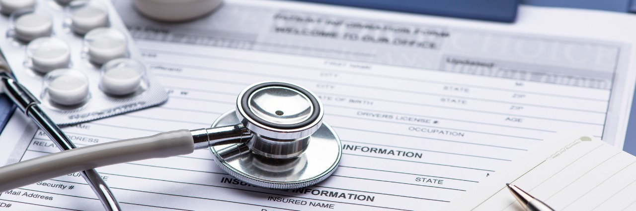 A Response to the Stigma Against Those Who Claim Disability Benefits Patient medical history document with pills and stethoscope