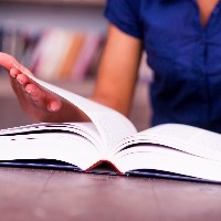 woman's hands turning pages of textbook