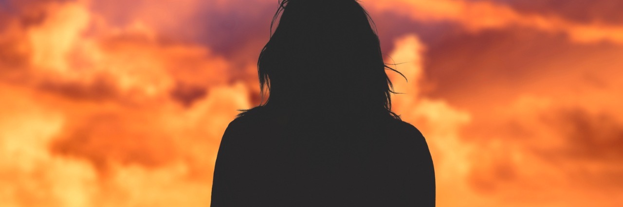 Silhouette of woman watching sunset sky