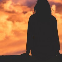 Silhouette of woman watching sunset sky