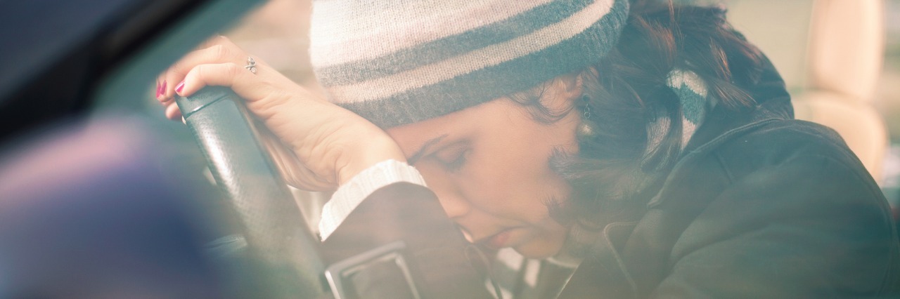 Coping With Anxiety in Daily Life sad and tired woman leaning her head on the steering wheel while sitting in the car