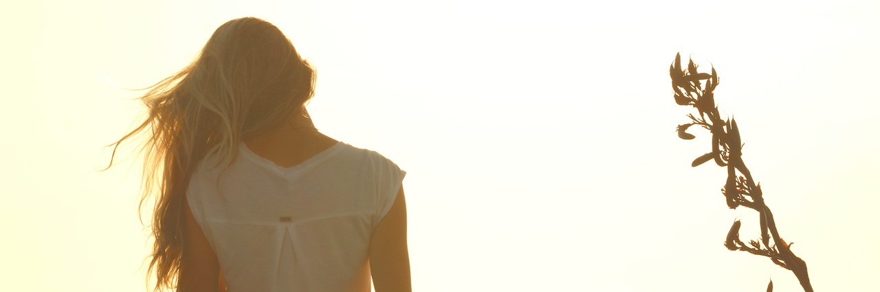 Why the Stigma Surrounding Mental Illness and Suicide Must Stop woman standing up, watching the sunset