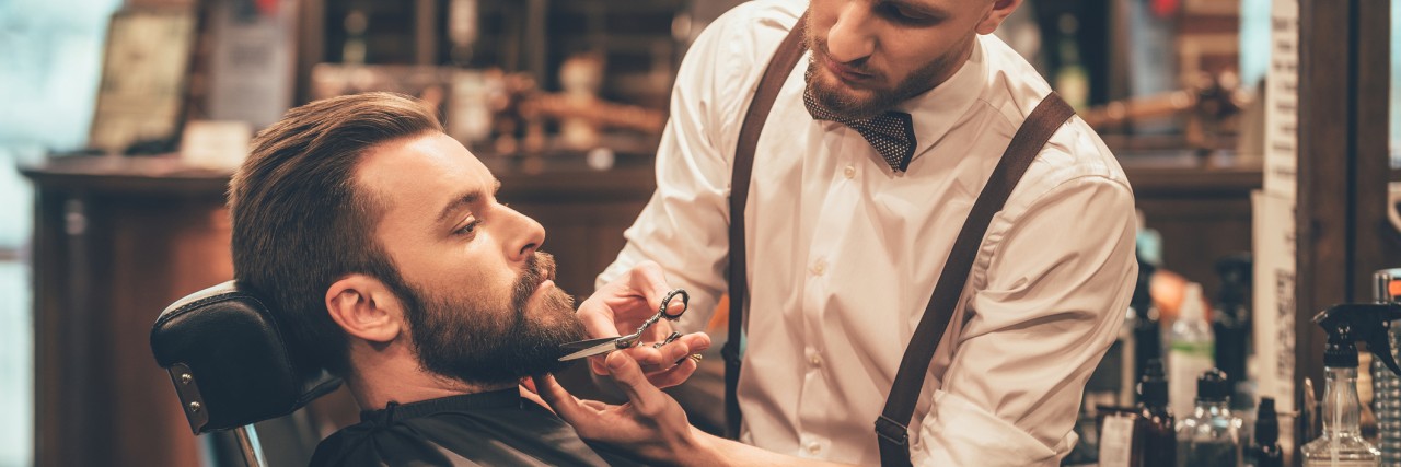 Challenging the Unpredictability of My Anxiety Side view of young bearded man getting beard haircut by hairdresser while sitting in chair at barbershop