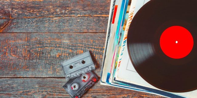 A stack of old vinyl records and cassette tapes are on the board
