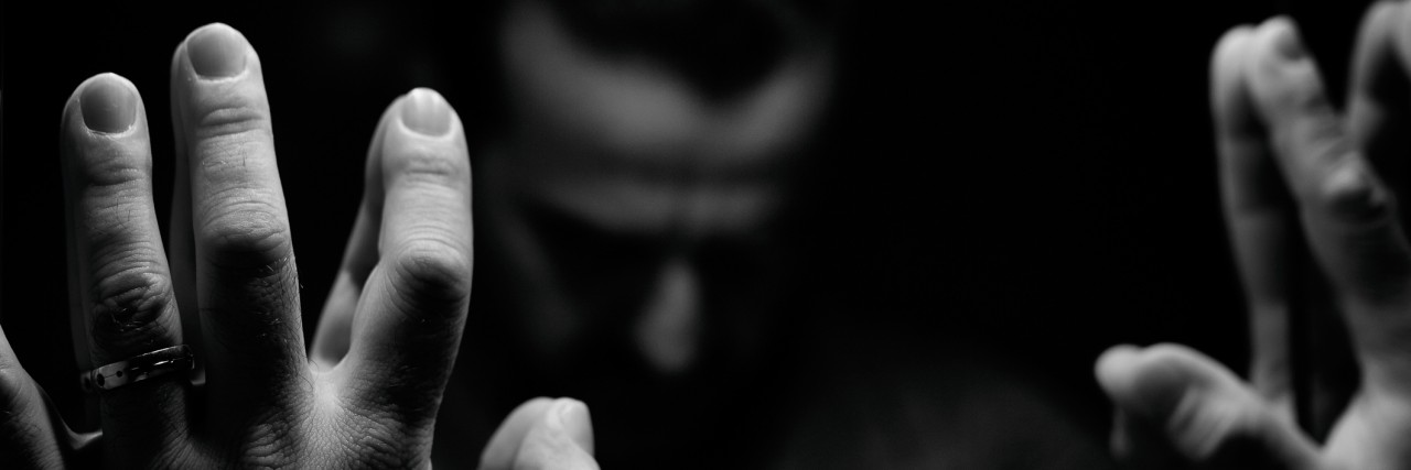 Man in despair with raised hands and bowed head in front of mirror