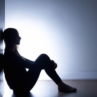 Teenager with depression sitting alone in dark room