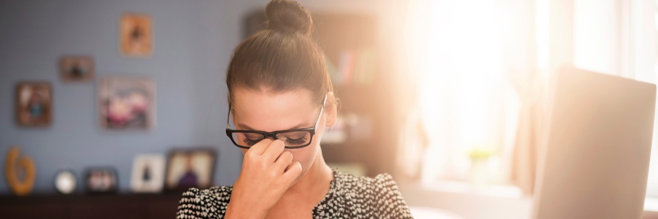 woman holding head while sitting at desk in office