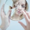 Girl looking in cracked mirror