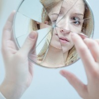 Girl looking in cracked mirror