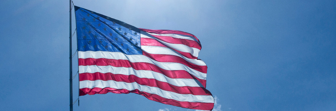 Coping With Anxiety About Trump as a Person With a Disability A waving U.S. Flag is back-lit in the afternoon sun.