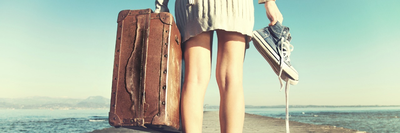 The Journey of Life With Chronic Illness woman standing on a dock and holding her suitcase and shoes