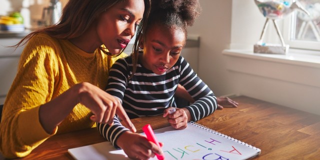 little black girl learning to write the alphabet with her mother