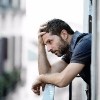 young man alone outside at house balcony terrace looking depressed