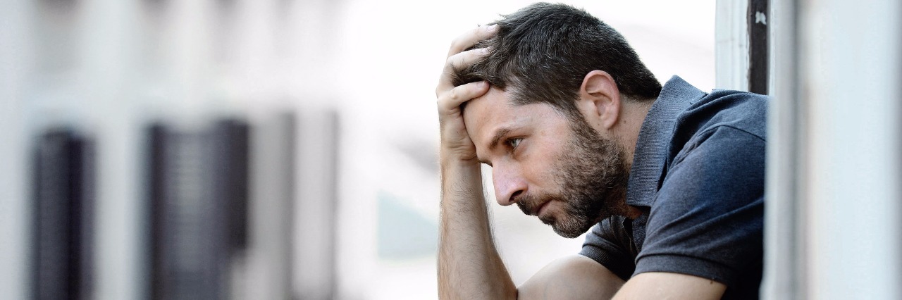 To the Men With Rheumatoid Arthritis Who Don't Feel Supported young man alone outside at house balcony terrace looking depressed