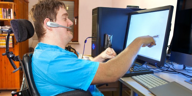 How to Make Technology More Inclusive for People With Disabilities Man with cerebral palsy using a computer.